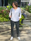Woman standing in front of a house wearing Miik's Asia mid-rise slim pant in charcoal with a white blouse.