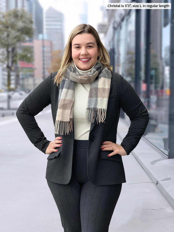 Miik model Christal (5'3", large) smiling wearing a charcoal blazer, a oatmeal turtleneck top with Miik's Asia mid-rise slim pant in charcoal wide pinstripe 