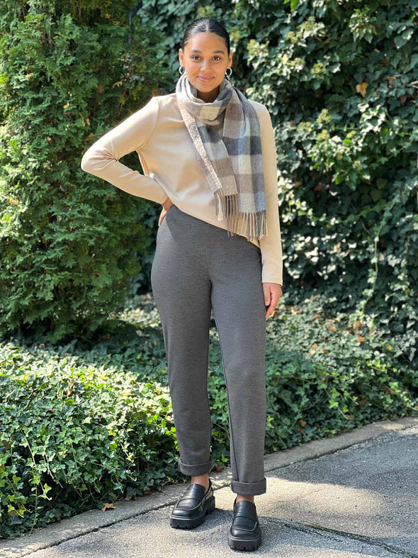 Miik model Meron (5'3", xsmall) smiling wearing Miik's Avery pull-on pant in granite melange with a wheat long sleeve top and a scarf in neutral tones