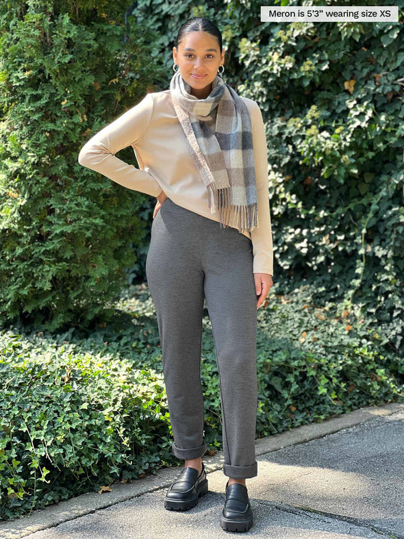 Miik model Meron (5'3", xsmall) smiling wearing Miik's Avery pull-on pant in granite melange with a wheat long sleeve top and a scarf in neutral tones