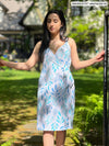 Woman standing in nature next to a fence looking away while wearing Miik's benton wrap dress in blue leaf pattern