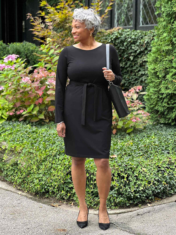 Miik model Keethai smiling while looking away wering Miik's Blair bamboo tie waist belt in black along with a long sleeve dress in the same colour