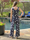 Miik model Johanna (five feet six, size xsmall) standing with her back towards the camera showing the back of Miik's Blakely faux-wrap dressy jumpsuit in blossom