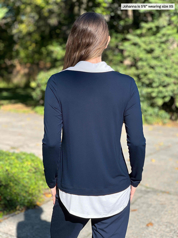 Miik model Johanna (5’6”, xsmall) standing with her back towards the camera showing the back of Miik's Carson collared faux-layer shirt in navy