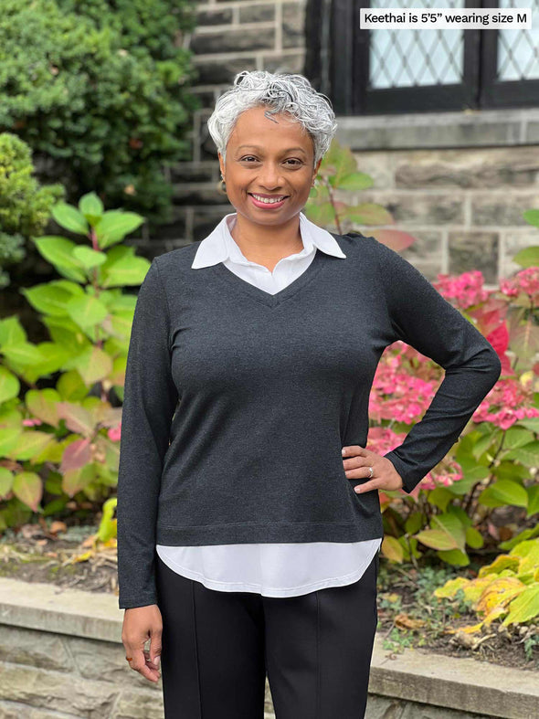 Miik model Keethai (5'5", maedium) smiling wearing Miik's Carson collared faux-layer shirt in charcoal with a black pant