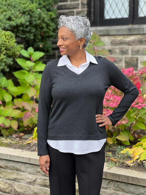 Miik model Keethai (5'5", maedium) smiling and looking away wearing Miik's Carson collared faux-layer shirt in charcoal with a black pant