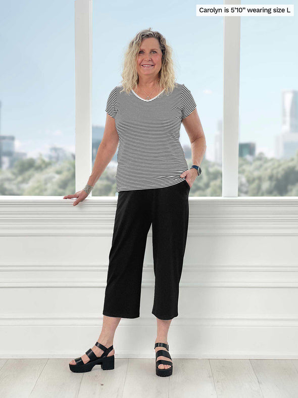 Miik model Carolyn (5'10", large) smiling wearing a mini stripe tee with Miik's Cassandra pull-on pocket capri pant in black
