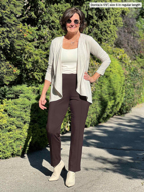 Miik founder Donna (size S, five foot 6) wearing the Christal pull-on pintuck ankle pant in chocolate brown in regular length with an off-white tank and matching cardigan.
