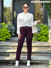 Miik model Meron (size XS, five foot three) wearing the regular length Christal dress pant in port burgundy with a tie-neck blouse in cream.