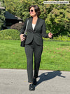 Woman walking wearing Miik's Christal pull-on pintuck ankle pant in charcoal in regular length with a matching blazer