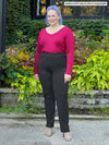 Miik model Kaitlin (size XXL, 5 foot 9) wearing Miik's Christal pintuck ankle pant in the long length in charcoal grey with a red long sleeve top.