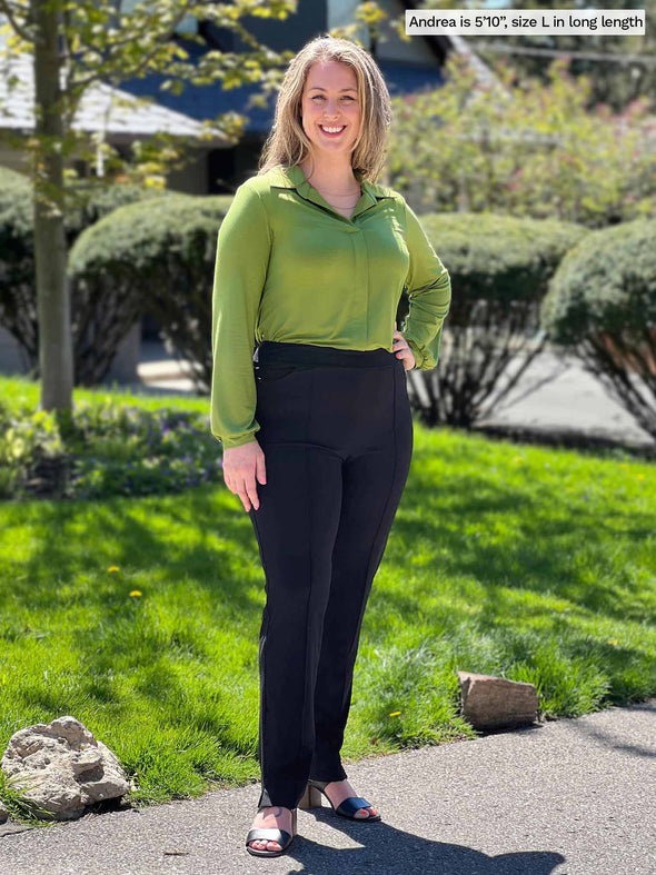 Miik model Andrea (5'10, large, tall) smiling wearing Miik's Christal pull-on pintuck ankle pant in black in long length with a collared shirt in green moss