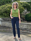 Miik model Liane (5'9", small) smiling wearing a green moss top with Miik's Christal pull-on pintuck ankle pant in navy in the long length