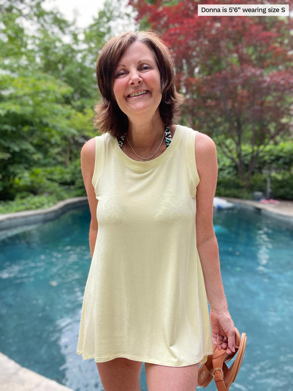 Woman standing in front of a pool wearing Miik's Dalya high-low flowy tunic tank in yellow as a swimsuit coverup.