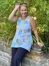 Woman standing in nature wearing Miik's Dalya high-low flowy tunic tank in leaf pattern with black pants.
