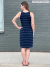 Miik model Johanna (five feet six, size xsmall) standing with her back towards the camera showing the back of Miik's Dani high neck sleeveless dress in navy wide pinstripe  