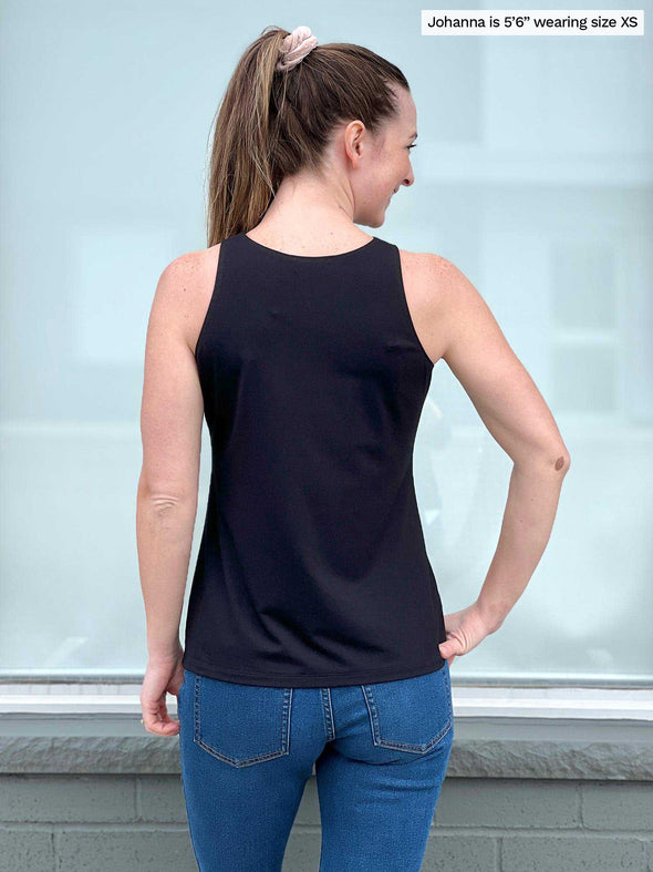 Miik model Johanna (five feet six, size xsmall) standing with her back towards the camera showing the back of Miik's Dolly high neck tank top in black