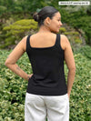 Miik model Meron (5’3”, xsmall) standing with her back towards the camera showing the back of Miik's Eline reversible shelf bra tank in black