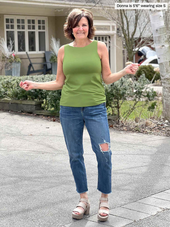 Miik founder Donna (5'6", small) smiling wearing a ripped jeans along with Miik's Eline reversible shelf bra tank in green moss reversed