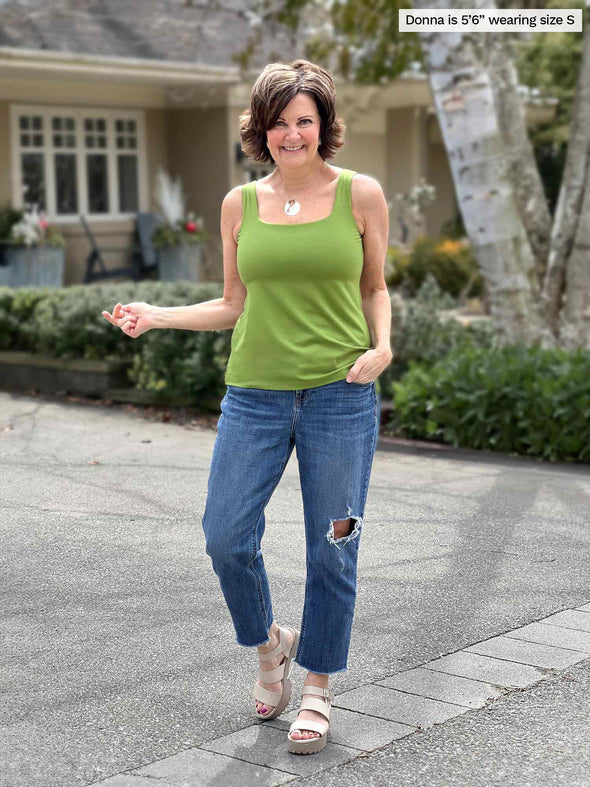 Miik founder Donna (5'6", small) smiling wearing a ripped jeans along with Miik's Eline reversible shelf bra tank in green moss 