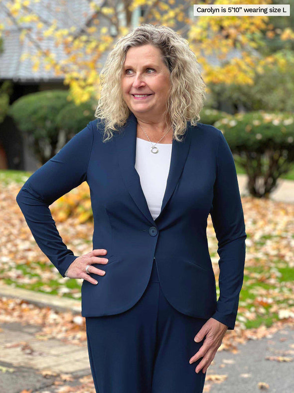 Miik model Carolyn (5'10, large) smiling while looking away wearing Miik's Emily soft blazer in navy along with a pant in the same colour and a white tank