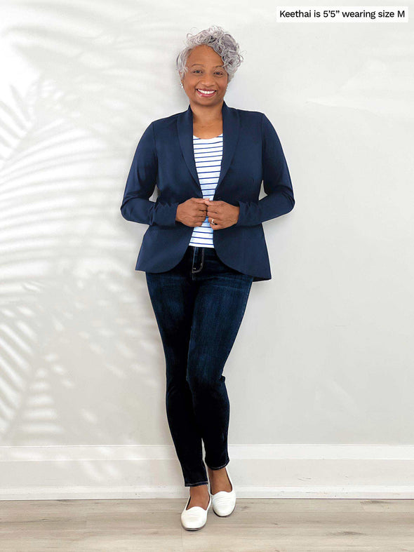 Miik model Keethai (5'5", medium) smiling wearing Miik's Emily soft blazer in navy along with a striped pencil skirt and a collared shirt in white 