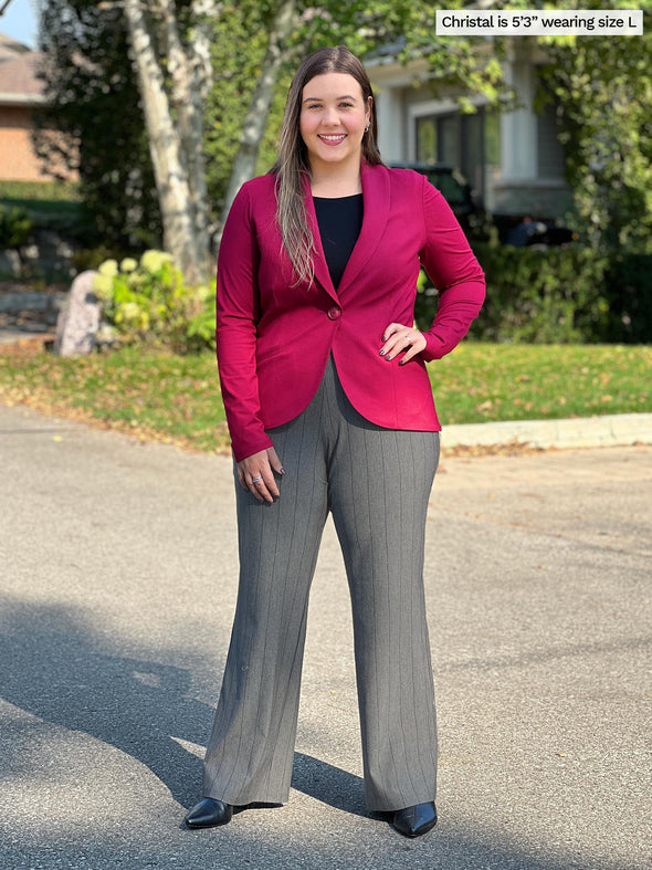 Miik model Christal (size L, 5 foot 3) wearing the Emily soft stretchy blazer buttoned in bordeaux red over a black tank with striped wide leg pants.