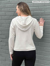 Woman standing with her back towards the camera showing the back of Miik's Essex cropped fleece hoodie in oatmeal melange