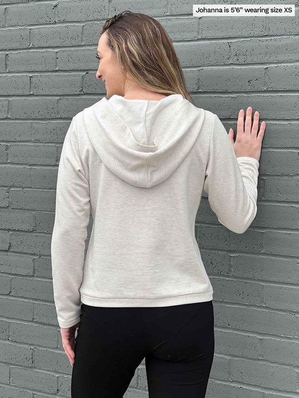 Woman standing with her back towards the camera showing the back of Miik's Essex cropped fleece hoodie in oatmeal melange