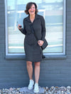 Woman standing in front of a window wearing Miik's Finian shirt collar long sleeve dress in charcoal and a crossbody purse