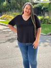 Miik plus size model Sarita (5'7", 2x) smiling wearing Miik's Gracelyn v-neck classic tee in black with jeans