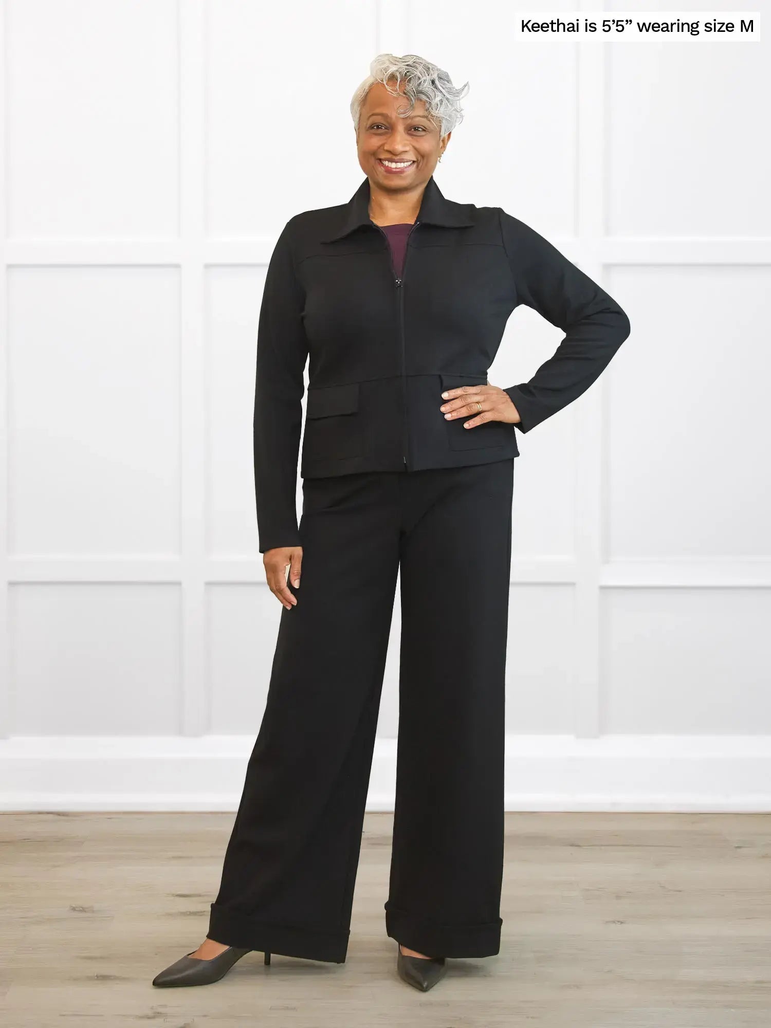 Woman wearing a black outfit standing against a white background 