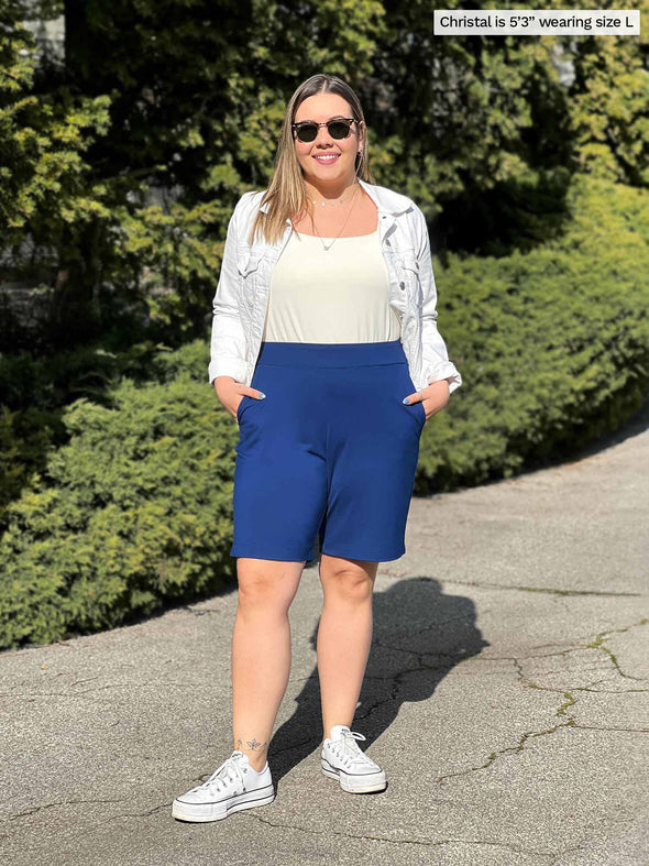 Miik model Christal (5'3", large) wearing Miik's Irelynn bermuda pocket short in ink blue with a natural tank and a white denim jacket 
