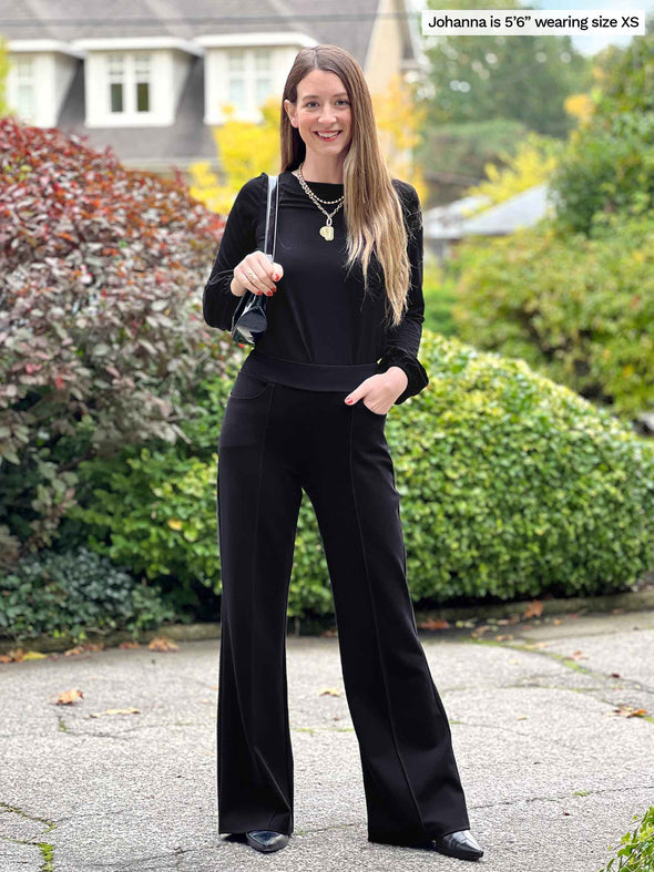 Miik model Johanna (5'6", xsmall) smiling wearing an all black outfit: Miik's Jeremy high waisted wide leg ponte pant and Sunniva long sleeve top