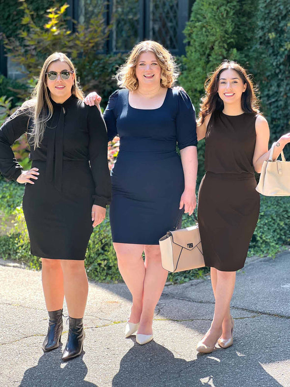 Miik models Christal, Bri and Yasmine (5'3 - 5'5 - 5'0) (large - xlarge - xsmall) standing next to each other in a sunny day all wearing Miik's Jilly pull-on pencil skirt in different colours: black, navy and dark chocolate. They are also matching the skirt colour with the top