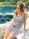 Woman siting next to a pool wearing Miik's Johanna open-back short romper in mini stripe
