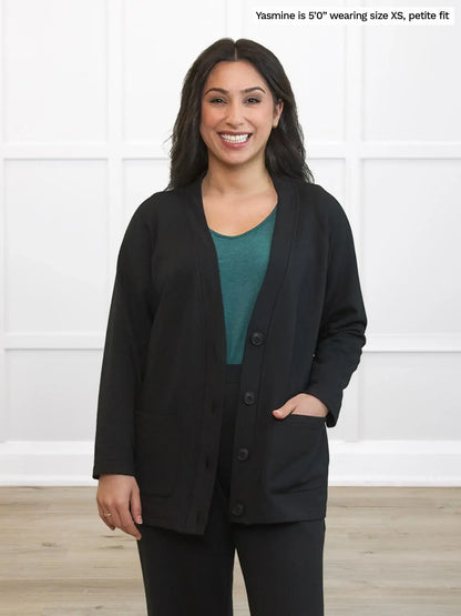 Woman wearing a black cardigan over a teal shirt with black pants. 