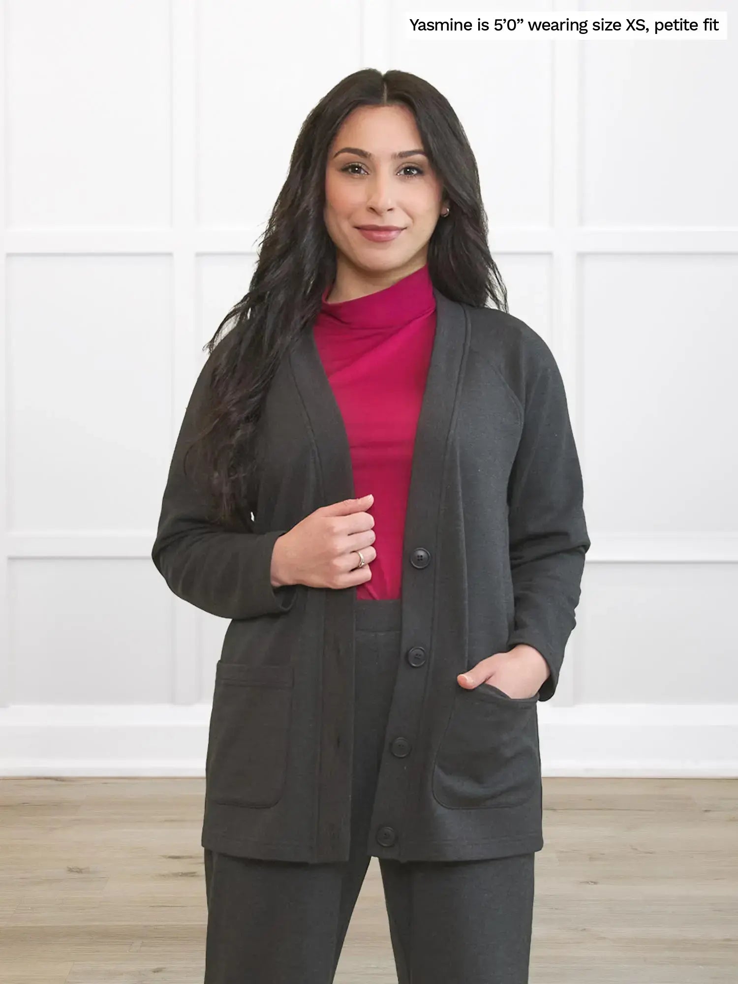 Woman wearing a gray blazer and pink shirt against a white background 