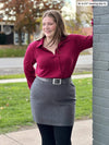 Woman standing next to a building wearing Miik's June simple skirt/scarf in grey with a red collared shirt.