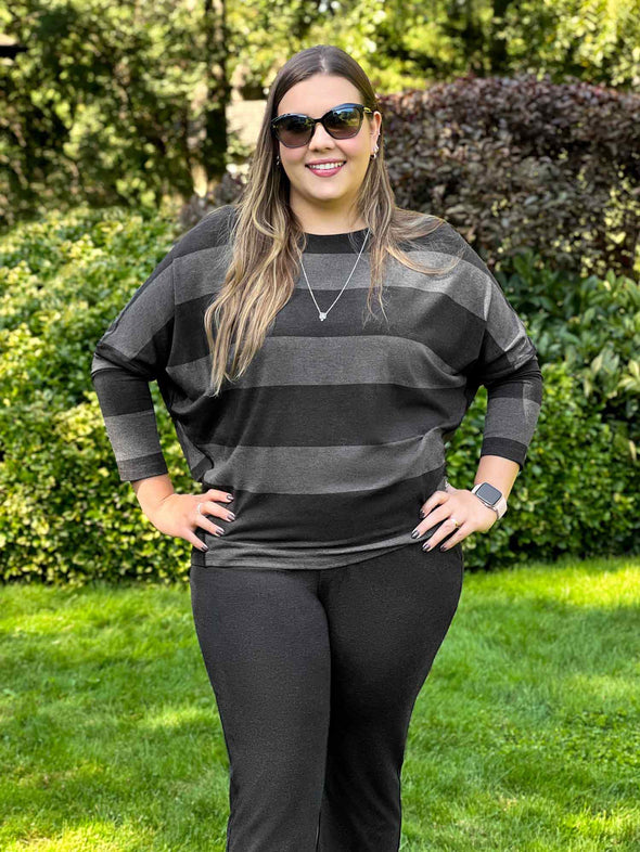 Miik model Christal (5'3", large) smiling wearing Miik's Kallyn slouchy dolman long sleeve top in dark ash stripe and a charcoal pant