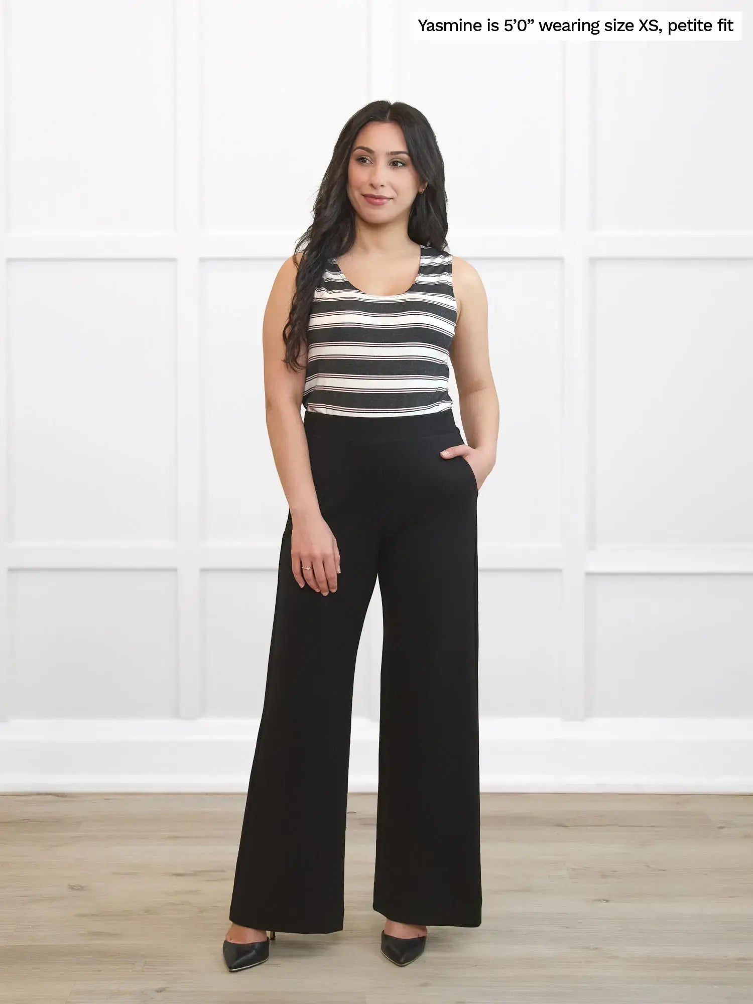 Woman wearing a striped top and black pants against a white background 