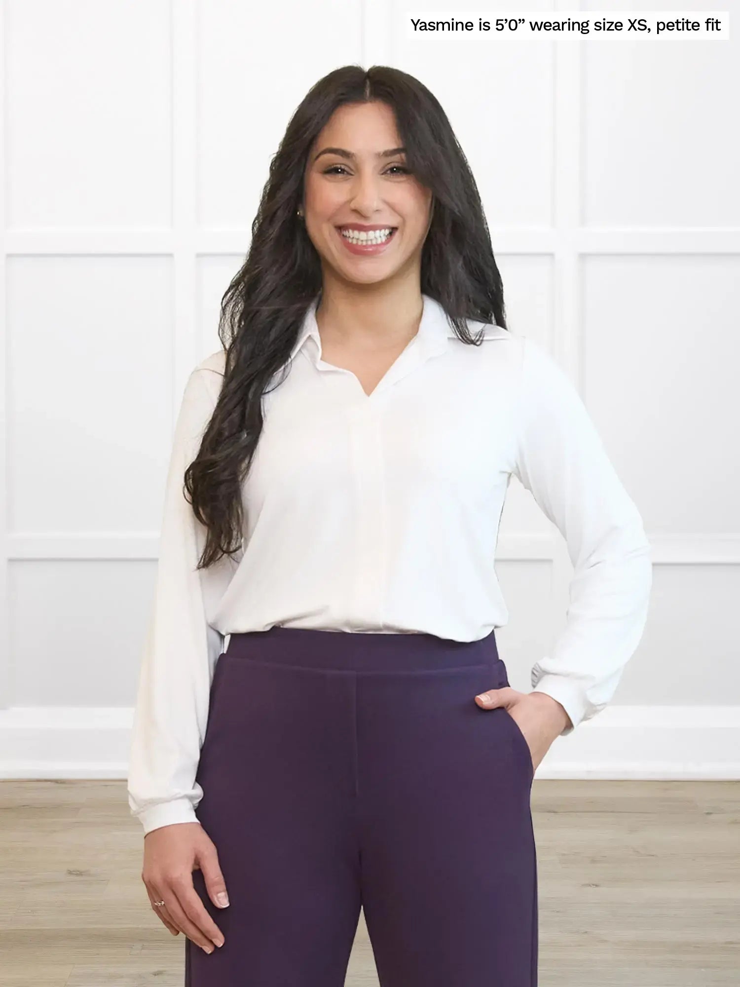Woman wearing a white blouse and purple pants against a white background 