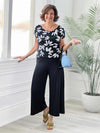 Miik founder Donna (5'6", small) smiling while standing in front of a window/white wall studio wearing Miik's Keethai wide leg culotte in black with a printed black/white flower tee