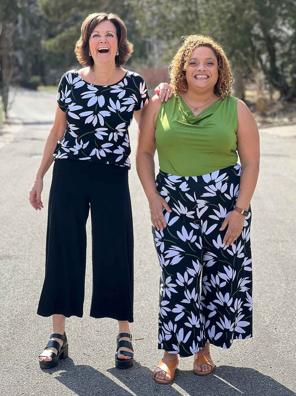 Miik founder Donna and model Carley laughing while standing next to each other both wearing Miik's Keethai wide leg culotte. Donna is wearing in the colour black while Carley is wearing in the white lily print 