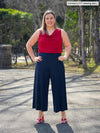 Miik model Christal (5'3", large) smiling wearing Miik's Keethai wide leg culotte in navy with a poppy red top and high heels 