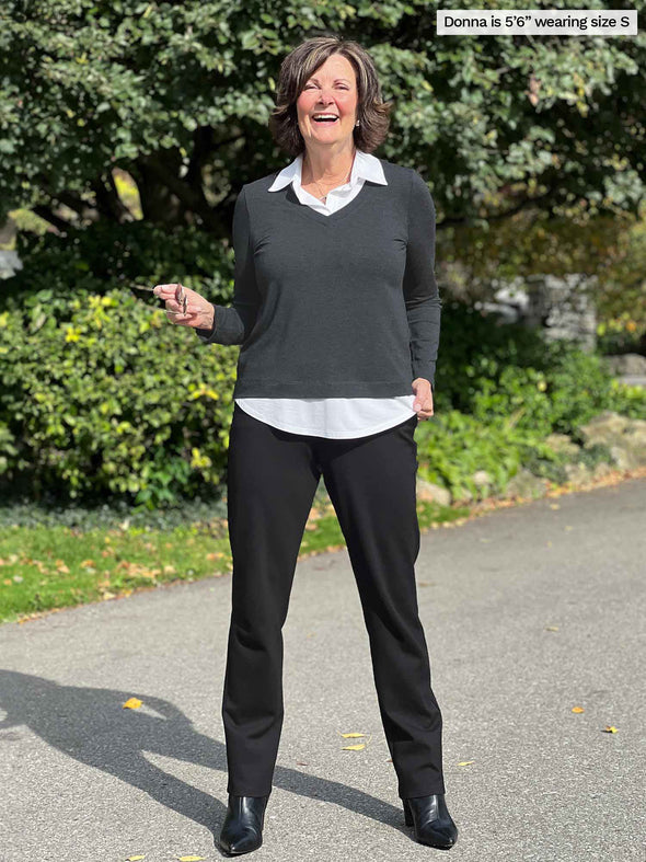 Miik founder Donna (5'6", small) laughing wearing a charcoal/white long sleeve top along with Miik's Keltie ponte mid-rise slim pant in black and boots 