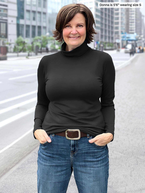 Miik founder Donna (5'6, small) smiling wearing Miik's Kerry turtleneck top in black with jeans 