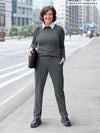 Woman standing on the streets wearing Miik's Kerry turtleneck top in grey over a collared shirt with charcoal pants.