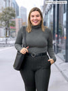 Woman standing on the streets wearing Miik's Kerry turtleneck top in grey with charcoal pants.