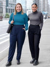 Miik models Christal and Meron standing next to each both wearing Miik's Nala pleated tapered pant and a turtleneck top. Christal is wearing the pant in navy with teal melange top while Meron is wearing the pant in black with a granite melange top
